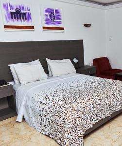 a bedroom with a bed and a red chair at ROYAL BASIN RESORT in Kumasi