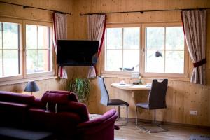 ein Wohnzimmer mit einem Tisch, Stühlen und Fenstern in der Unterkunft Konradgut 11 - Ruhe und Aussicht auf 1140m in Sankt Lorenzen ob Murau