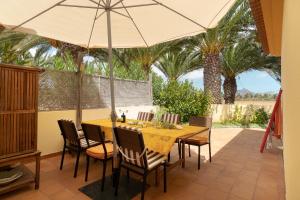 ein Esszimmer mit einem Tisch, Stühlen und einem Sonnenschirm in der Unterkunft CASA NA PRAIA in Vila Baleira