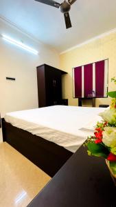 um quarto com uma cama com lençóis brancos e flores em Sunny Daze em Cherai Beach