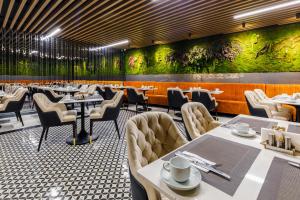 restauracja ze stołami i krzesłami oraz zieloną ścianą w obiekcie Euro Design Hotel w Stambule
