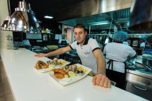 Un homme debout dans une cuisine avec une assiette de nourriture dans l'établissement Accra Luxury Apartments @ Pearl, à Accra