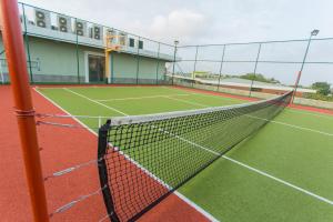 a tennis court with a net in front of a building at Accra Luxury Apartments @ Pearl in Accra