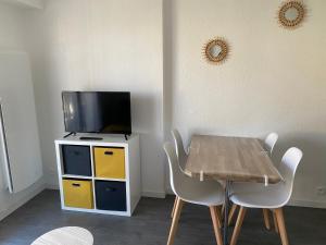 uma sala de jantar com uma mesa e uma televisão em Cabourg T2 cosy avec accès direct plage em Cabourg