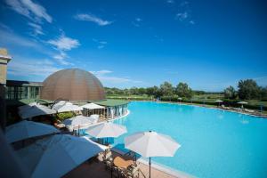 a large swimming pool with umbrellas and a building at Cosmopolitan Golf & Beach Resort in Tirrenia