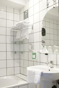 Baño de azulejos blancos con lavabo y bañera en Splendid Hôtel, en LʼÎle-Rousse