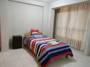 a bedroom with a bed with a striped blanket and a window at La casa de Chepita in Cusco