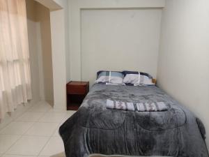 uma cama num quarto branco com uma colcha em La casa de Chepita em Cusco