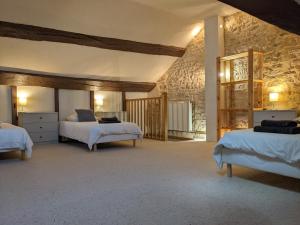 a bedroom with two beds and a stone wall at La Licorne - Renovated Townhouse in St Gengoux in Saint-Gengoux-le-National