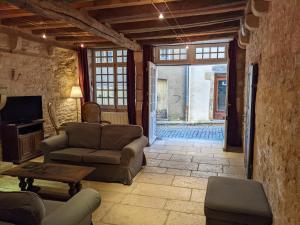 a living room with a couch and a table and a tv at La Licorne - Renovated Townhouse in St Gengoux in Saint-Gengoux-le-National