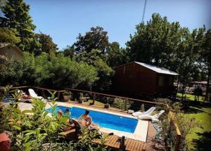 a swimming pool with people in a yard with a house at Cabañas María Julia Tigre in Tigre