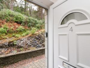 a white door with a window next to a path at 4 River Court in Invergarry