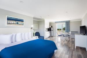 a hotel room with a blue bed and a kitchen at Hartman's Briney Breezes Beach Resort in Montauk