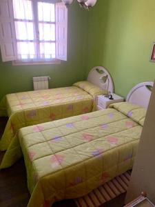 2 camas en una habitación con paredes verdes en Apartamento en Complejo Residencial con Parking, en Comillas