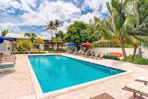 a pool with chairs and palm trees in a yard at Beach Living at Island Pine Villas (BLJ) in George Town