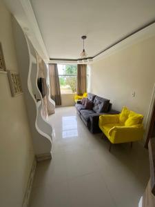 uma sala de estar com um sofá e cadeiras amarelas em Bartole em Angra dos Reis