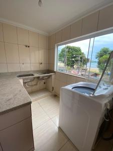 uma casa de banho com uma máquina de lavar roupa e uma janela em Bartole em Angra dos Reis