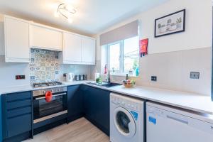a kitchen with blue cabinets and a washer and dryer at Windy House in Sheffield