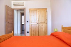 sypialnia z pomarańczowym łóżkiem i drewnianą szafą w obiekcie Appartamenti Marinelli - Santa Maria di Leuca w mieście Leuca