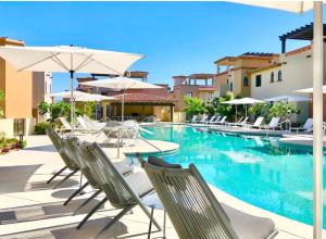 a pool with chairs and umbrellas next to a hotel at Mavila at Quivira Golf & Sea Community plus PB Beach Access on Medano Beach in Cabo San Lucas