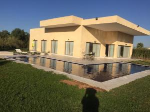 a person standing in front of a house with a swimming pool at Villa Jamila -Villa de luxe a Marrakech in Marrakesh