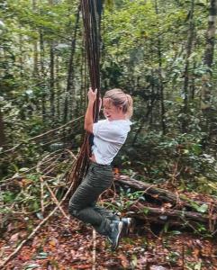 una joven balanceándose sobre un árbol en el bosque en Anaconda Amazon Island, en Manaus
