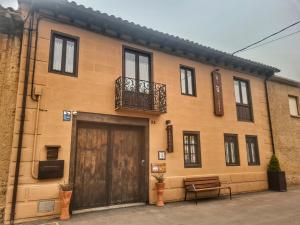 ein Gebäude mit einer Holztür und einem Balkon in der Unterkunft Albergue El Encanto in Villares de Órbigo