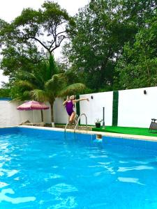 Uma mulher está a saltar para uma piscina. em Hotel Oro Blanco em Atacames