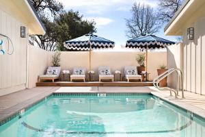 ein Pool mit Stühlen und Sonnenschirmen neben einem Haus in der Unterkunft Hotel Ynez in Solvang
