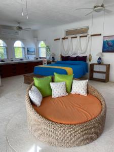 a bedroom with a bed and a rattan couch at Private Pool With Stunning Views Of The Ocean The Ultimate Spot To Relax And Unwind in Akumal