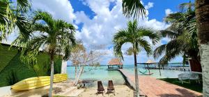 einen Strand mit Palmen und Stühlen sowie einen Pier in der Unterkunft Casita Maya Bacalar in Bacalar