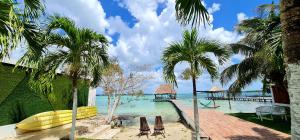 a beach with palm trees and chairs and a pier at Casita Maya Bacalar in Bacalar