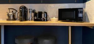 a counter with a microwave and a coffee maker and stools at The Seven Stars in Timsbury +6 photos