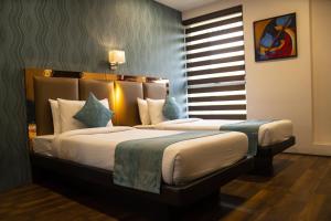 a hotel room with two beds in a bedroom at The Opus Kolkata - A Boutique Hotel in Kolkata
