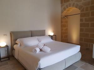 białe łóżko z dwoma rolkami ręczników w obiekcie Residence Masseria Santa Lucia w mieście Matera +37 zdjęć