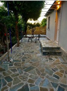 a stone patio with two benches and a tree at Dina’s house in Argostoli