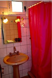 a bathroom with a sink and a red shower curtain at Dina’s house in Argostoli