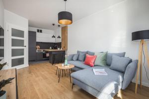 ein Wohnzimmer mit einem blauen Sofa und einem Tisch in der Unterkunft TS New Town Apartments in Stettin