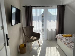 ein Schlafzimmer mit einem Stuhl, einem Bett und einem Fenster in der Unterkunft Apartament Wierzawice in Wierzawice