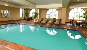 a swimming pool with chairs and a table in a building at Woolley's Classic Suites Denver Airport in Aurora