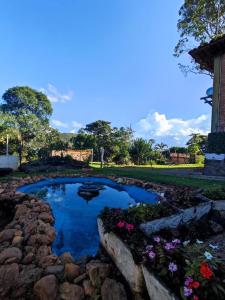 um pequeno lago com pedras e flores num quintal em Quinta da Bela Vista em Caeté