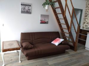 un sofá marrón en una sala de estar con una escalera en Les petits gites en Ernée