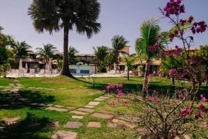 a garden with pink flowers and palm trees at Geriba Beach apart hotel apt504 in Búzios