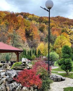 un poste de luz en un jardín con árboles y hojas de otoño en Hotel RAS Pazarište, en Novi Pazar