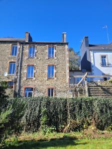 an old stone building behind a hedge at La coulée pilette in Callac