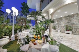a restaurant with white tables and chairs and palm trees at Ariminum Hotel in Rimini