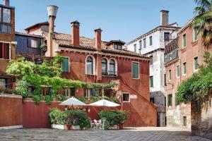un edificio rojo con mesas y sombrillas en un patio en Locanda Fiorita, en Venecia