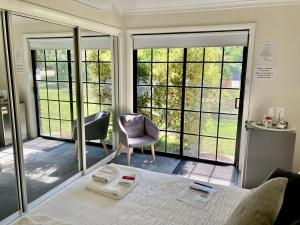 a room with a bed and two chairs and windows at Rosewhite House in Myrtleford