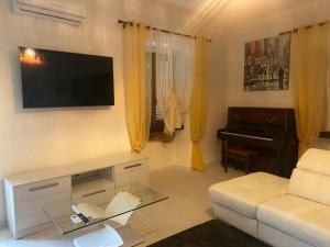 a living room with a white couch and a piano at white appartament in Bagnolo Piemonte