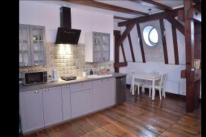 a kitchen with white cabinets and a table and a window at Apartament na Piernikarskiej in Toruń